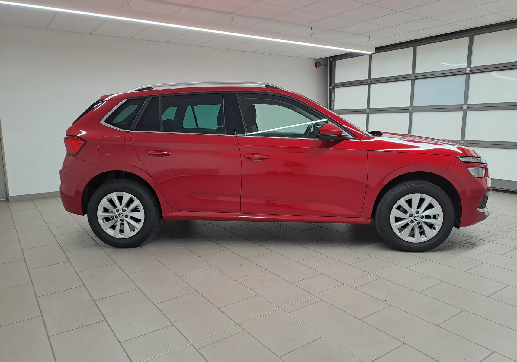 Profil côté droit du Skoda Kamiq 2024 en Rouge Velvet métallisé, avec jantes alliage et caméra de recul visible.