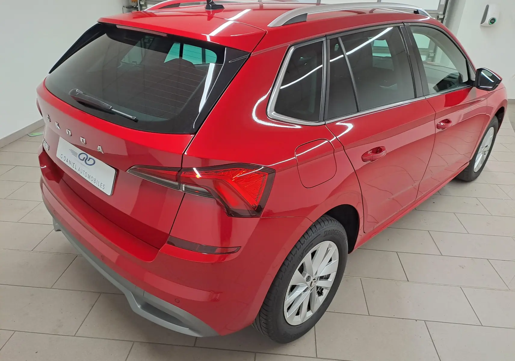 Vue 3/4 arrière droite d'un Skoda Kamiq 2024 Rouge Velvet avec feux arrière LED et jantes alliage.