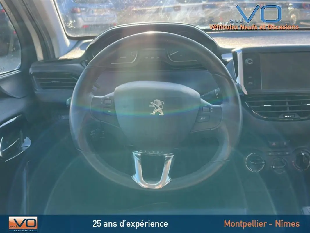 Intérieur de la Peugeot 208 blanc 2015, vue centrée sur le volant avec tableau de bord et écran tactile visibles.