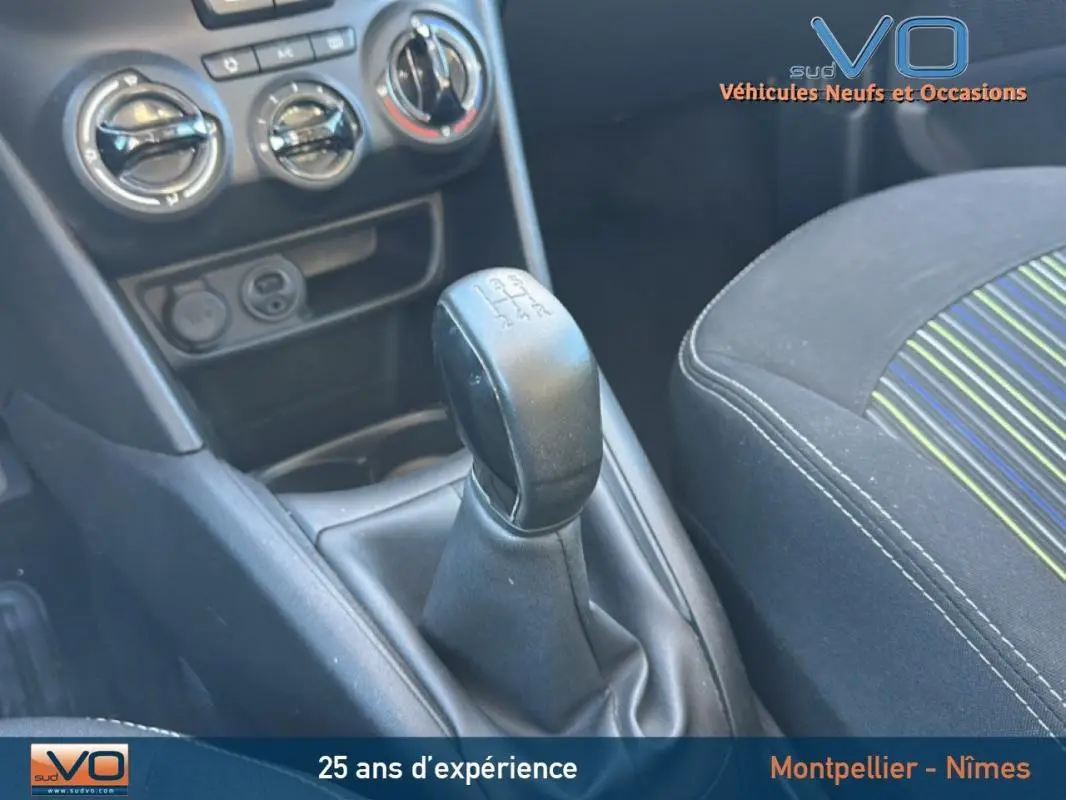 Gros plan sur le levier de vitesses manuel et la console centrale du Peugeot 208 blanc, avec siège avant tissu rayé visible.