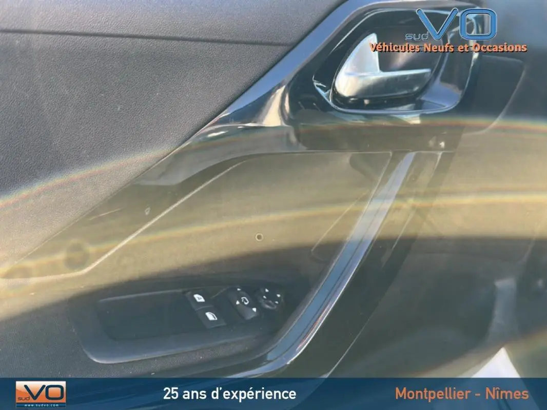 Détail de la porte avant gauche noire de la Peugeot 208 Urban Soul avec commandes électriques et poignée chromée.