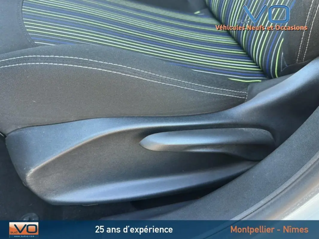 Gros plan sur le siège conducteur à réglage manuel de la Peugeot 208 blanc, tissu rayé vert et bleu visible.