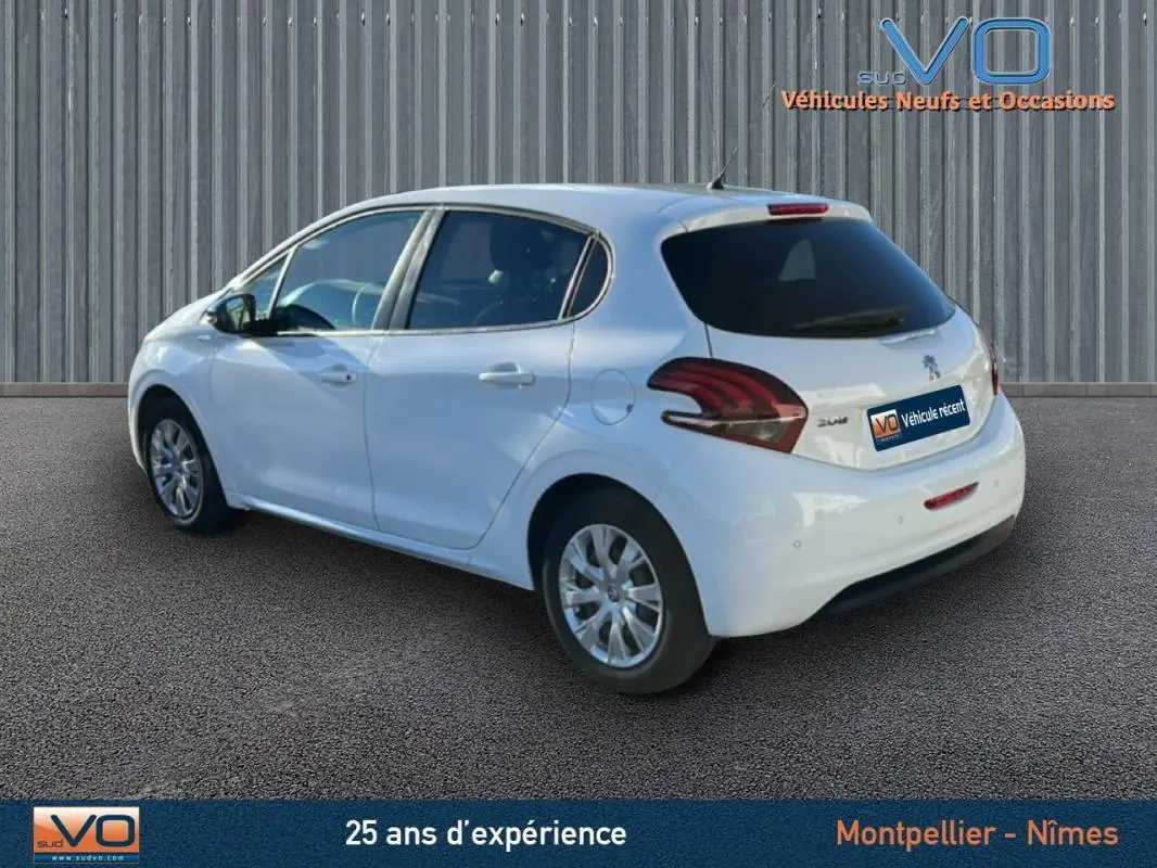 Vue 3/4 arrière droite d'une Peugeot 208 blanche de 2015 avec jantes classiques 15 pouces et vitres teintées arrière.