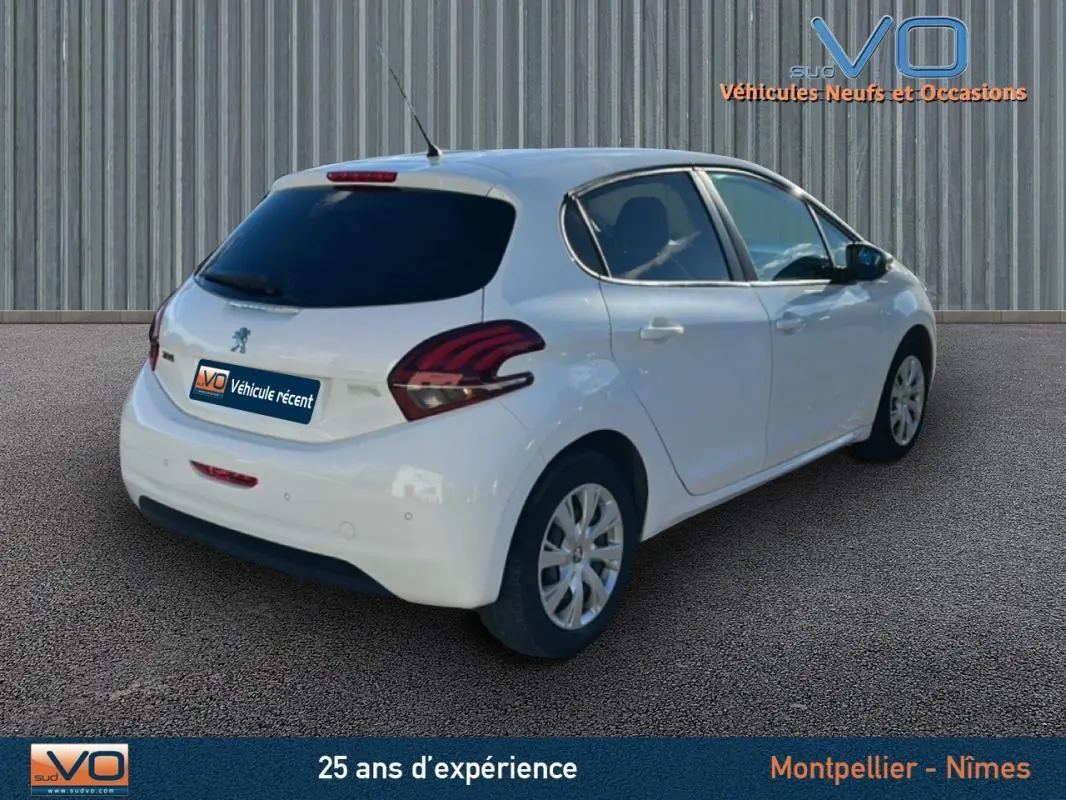 Vue 3/4 arrière droite d'une Peugeot 208 blanche de 2015 avec jantes classiques 15 pouces et vitres teintées arrière.