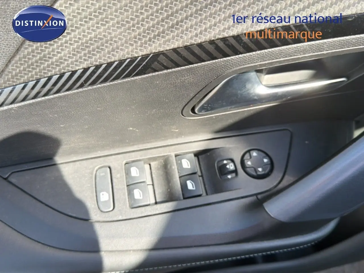 Gros plan sur les commandes de lève-vitres et rétroviseurs côté conducteur d'une Peugeot 2008 gris platinium.
