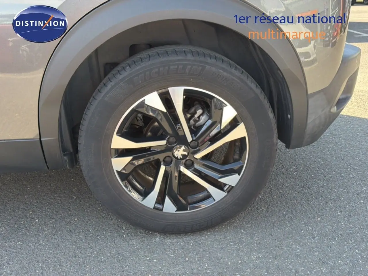 Gros plan sur la roue avant droite avec jante bi-ton noire et argentée du Peugeot 2008 gris platinium.