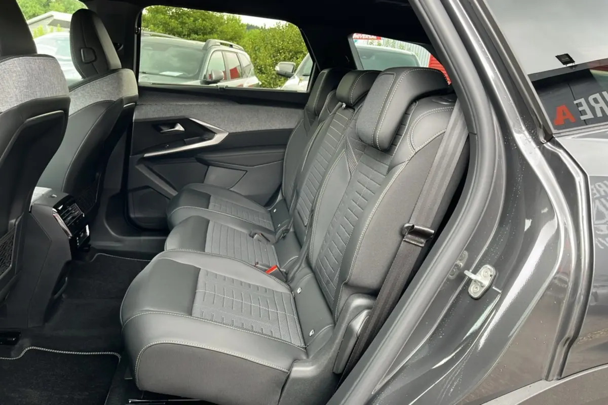 Vue intérieure côté gauche montrant la banquette arrière en cuir et tissu gris du Peugeot 5008 Hybrid 2025 toit noir.
