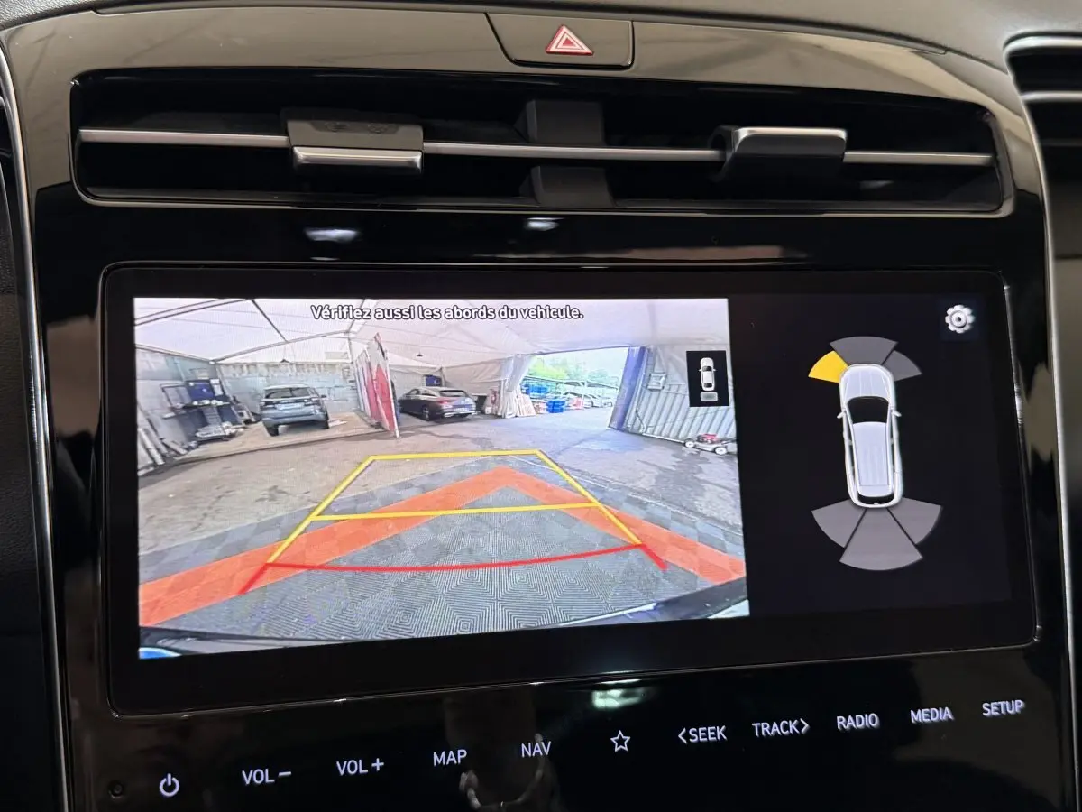 Écran tactile du tableau de bord montrant la caméra de recul et les capteurs de stationnement du Hyundai Tucson noir.