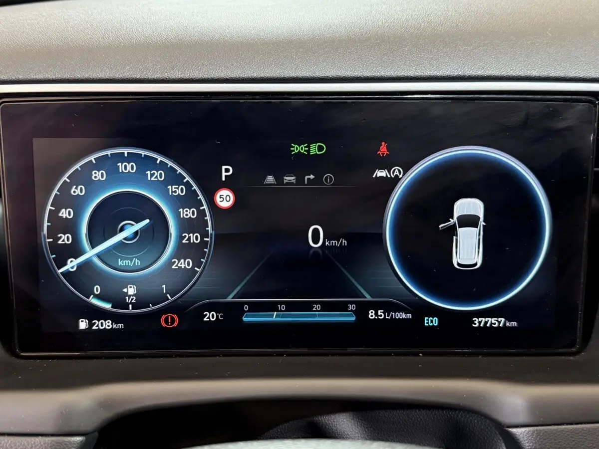 Affichage numérique du tableau de bord du Hyundai Tucson hybride 2021 montrant vitesse, consommation et alertes.