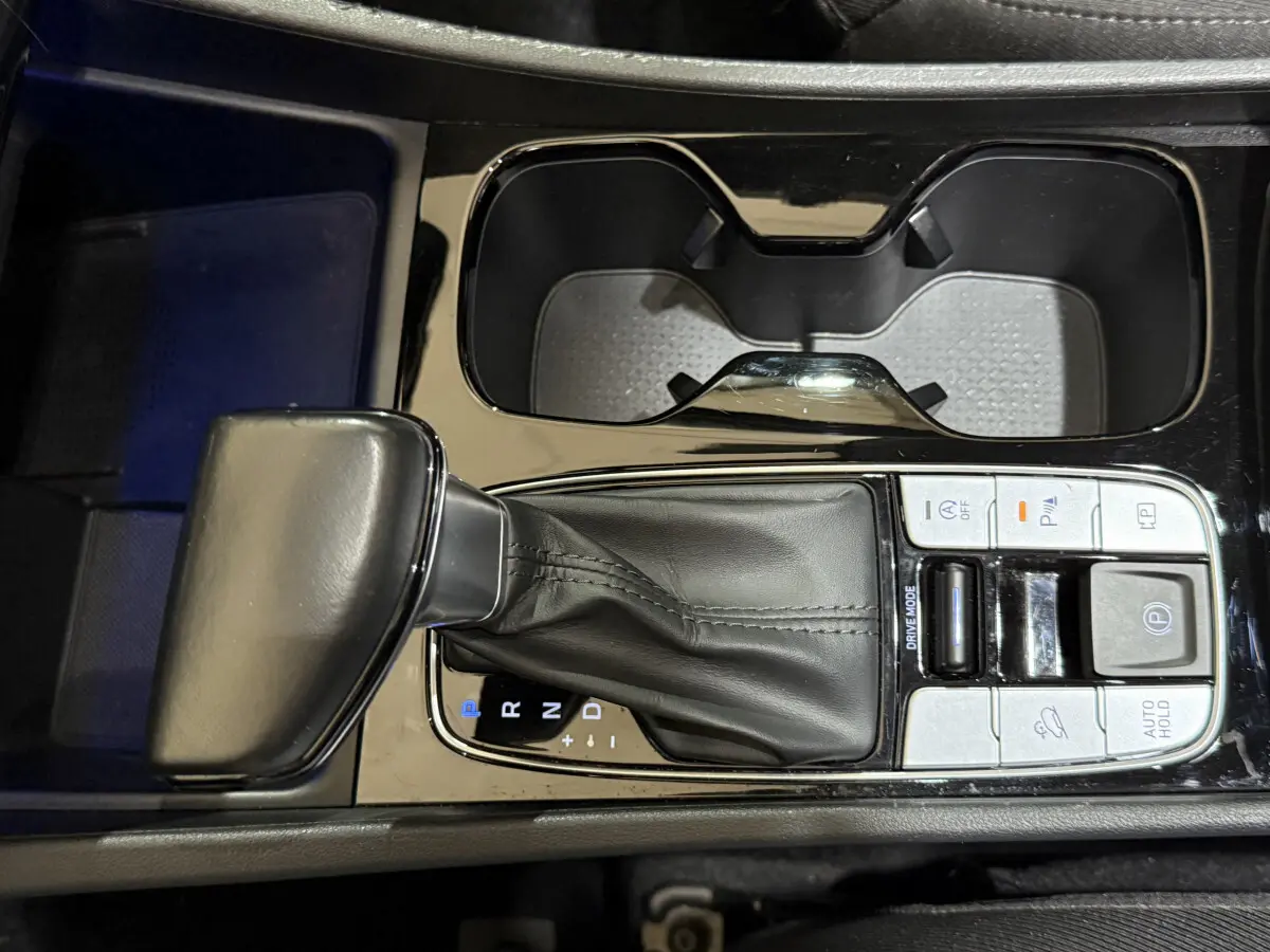 Vue rapprochée de la console centrale noire du Hyundai Tucson 2021, montrant le levier de vitesse automatique et les commandes adjacentes.