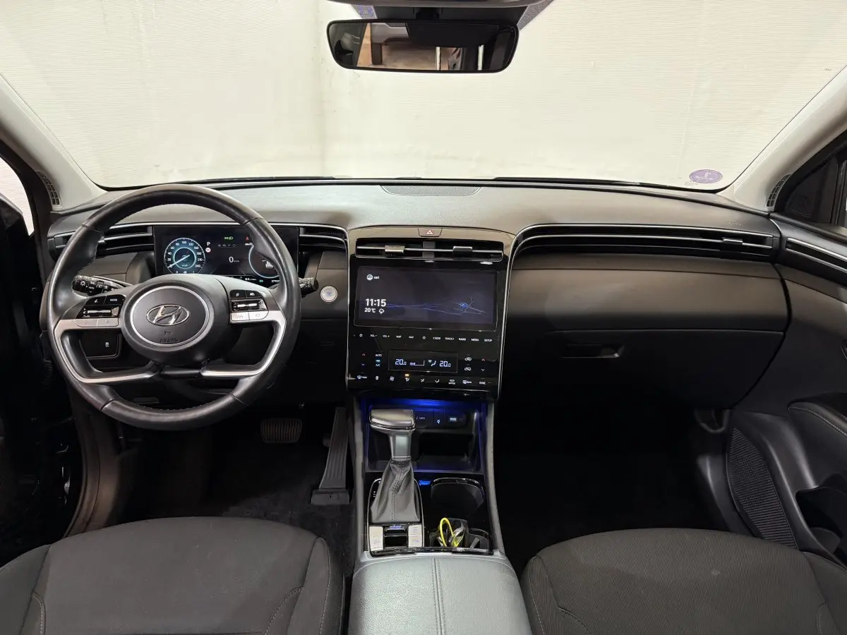 Intérieur noir du Hyundai Tucson 2021 vu de face, avec tableau de bord numérique et écran tactile central lumineux.