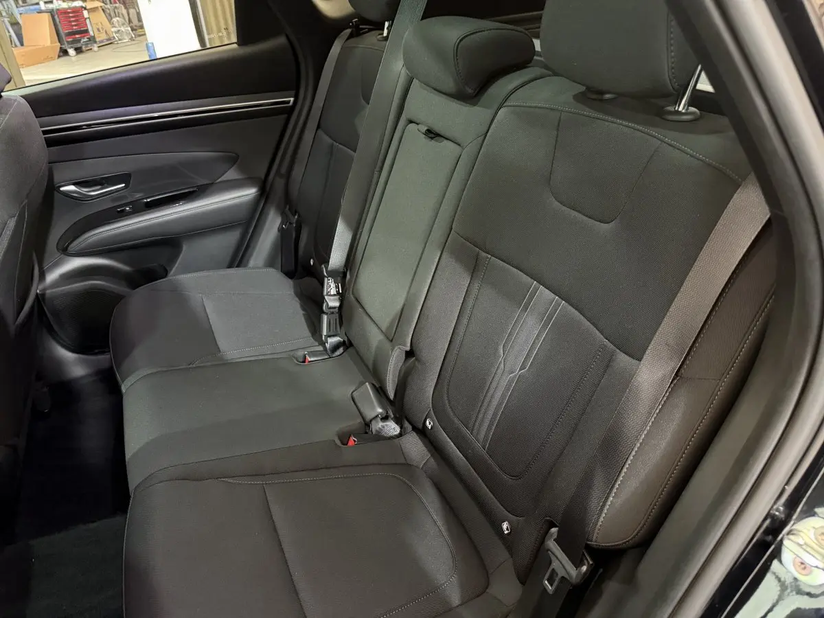 Vue intérieure des sièges arrière noirs du Hyundai Tucson 2021, avec ceinture de sécurité et garniture tissu.