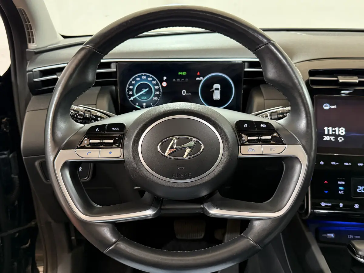 Vue rapprochée du volant cuir et alu du Hyundai Tucson 2021 avec tableau de bord numérique et écran tactile central.