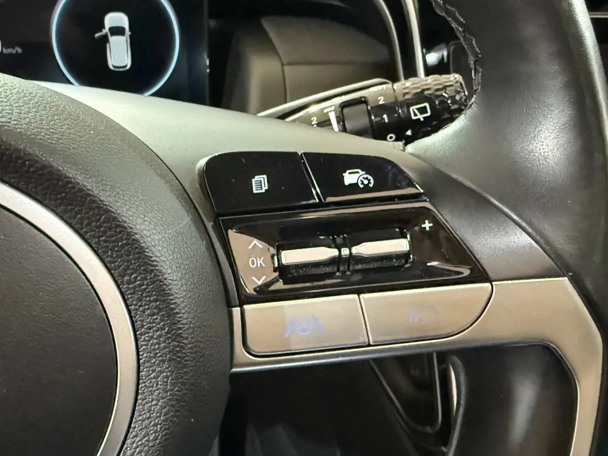 Gros plan sur les commandes du volant cuir noir du Hyundai Tucson 2021, avec boutons multifonctions et régulateur de vitesse.