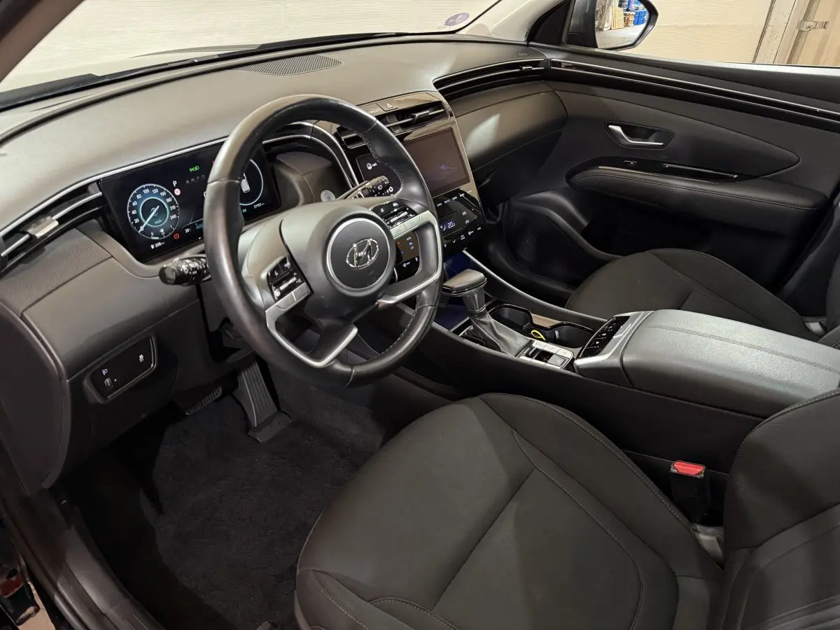 Intérieur noir du Hyundai Tucson 2021 vu côté conducteur, avec tableau de bord numérique et écran tactile central.