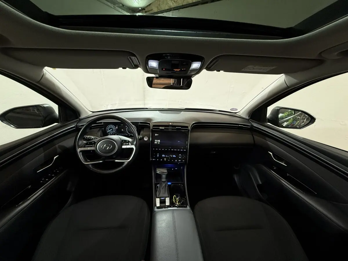 Intérieur noir du Hyundai Tucson 2021, vue frontale du tableau de bord avec écran tactile et volant multifonctions.
