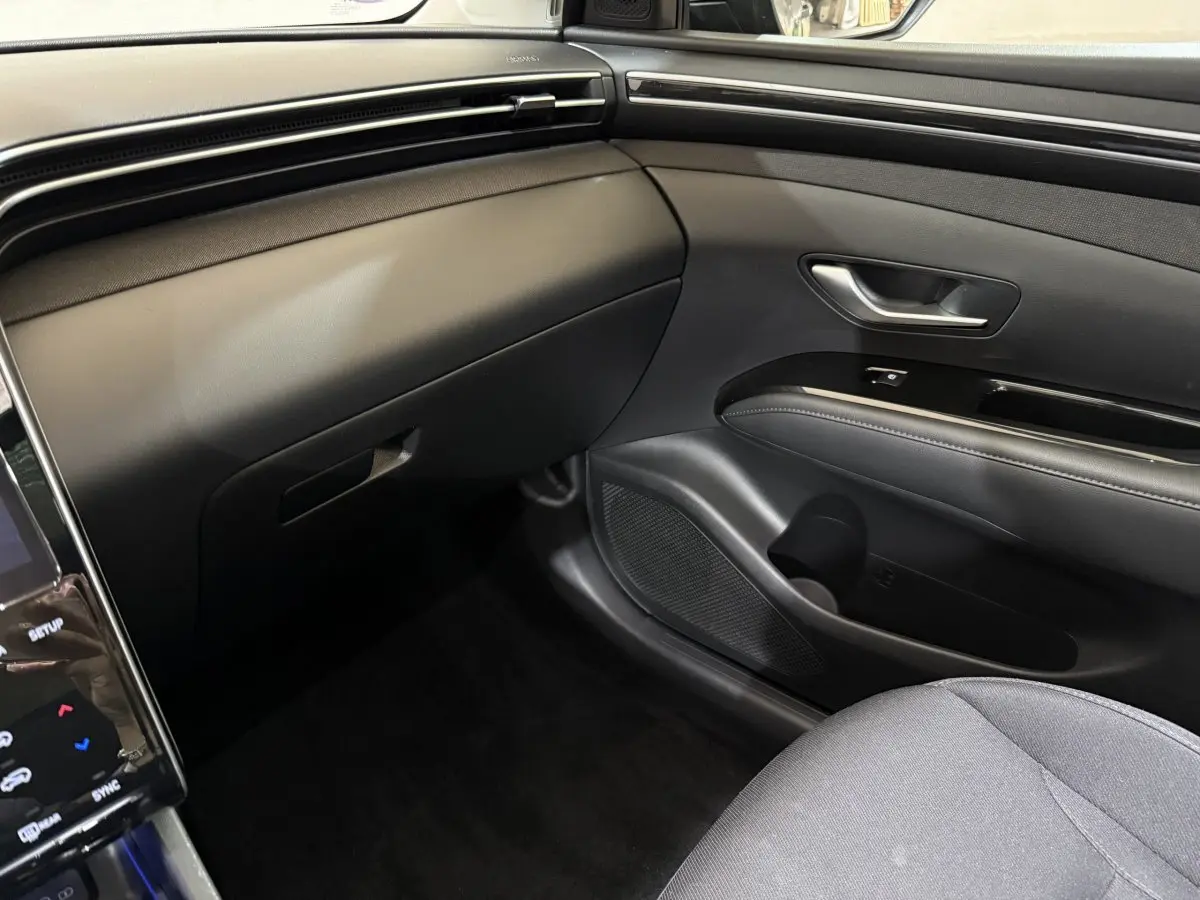 Intérieur côté passager du Hyundai Tucson noir 2021, avec tableau de bord et porte en matériaux noirs élégants.