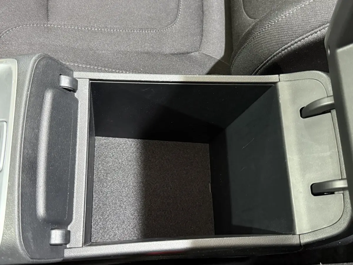 Vue plongeante sur le rangement central ouvert du Hyundai Tucson noir, montrant l'intérieur spacieux et les finitions en tissu.