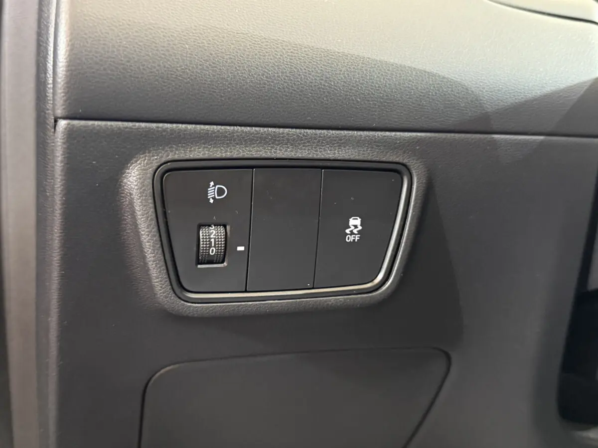 Gros plan sur les commandes de réglage des phares et de l'ESP à gauche du tableau de bord du Hyundai Tucson noir 2021.