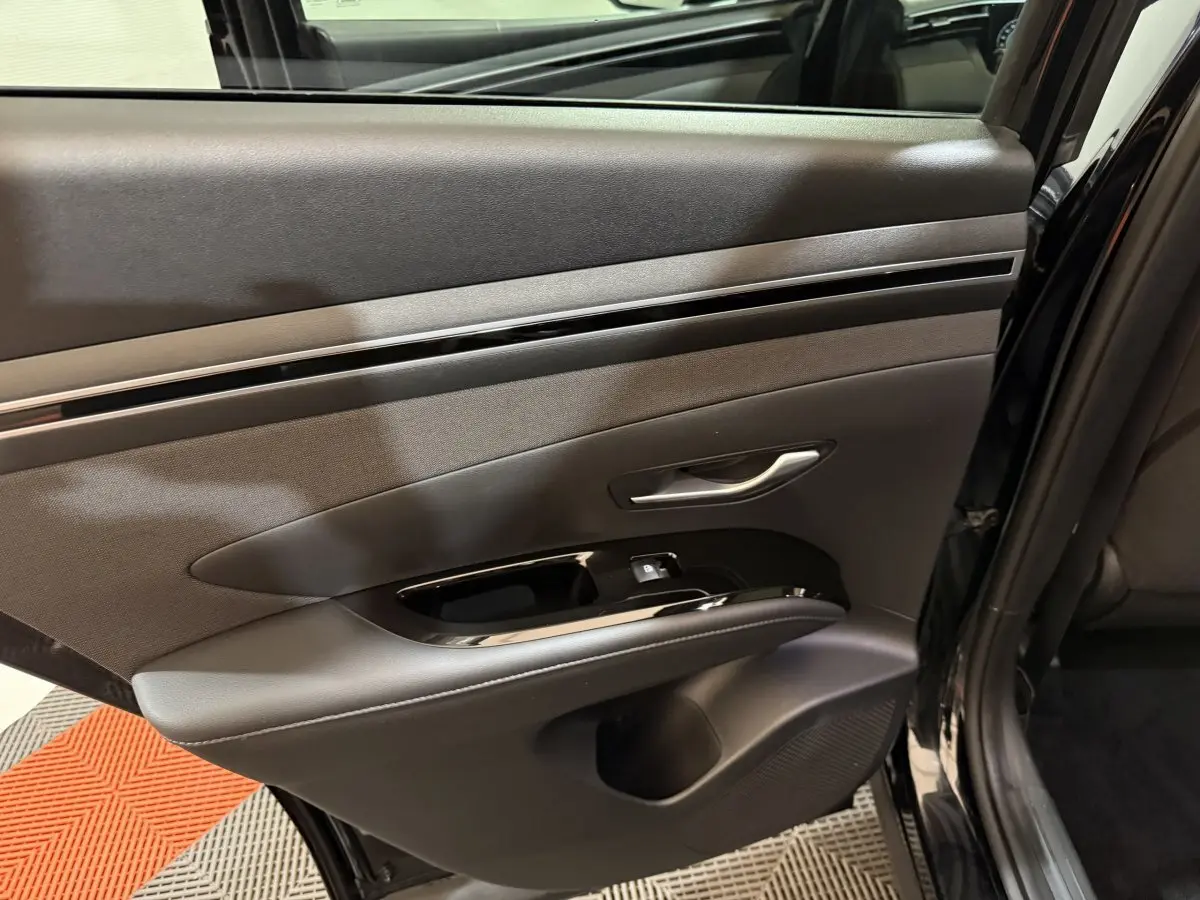 Gros plan sur la porte arrière gauche noire du Hyundai Tucson 2021, avec poignée argentée et commandes de fenêtre intégrées.