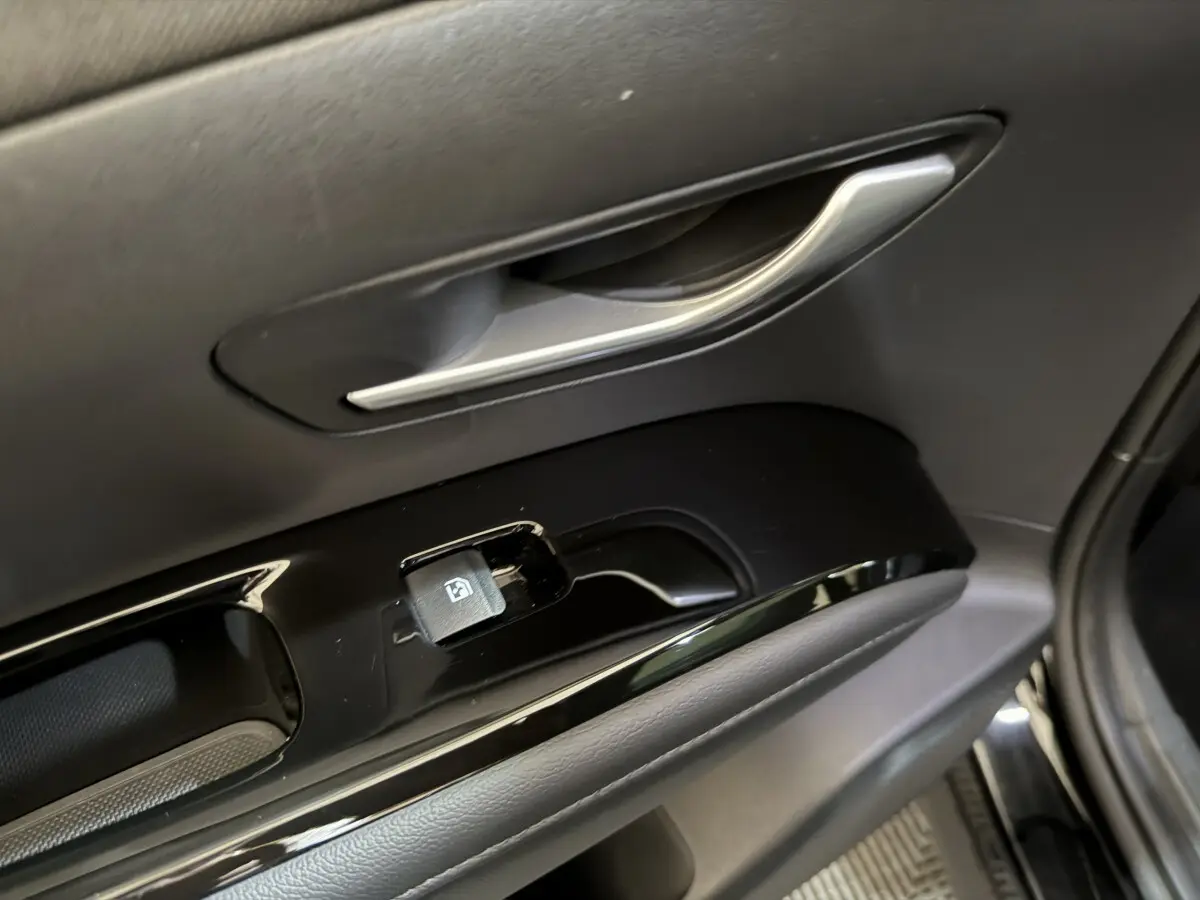 Poignée et commande de lève-vitre côté conducteur du Hyundai Tucson noir, intérieur en plastique noir brillant.