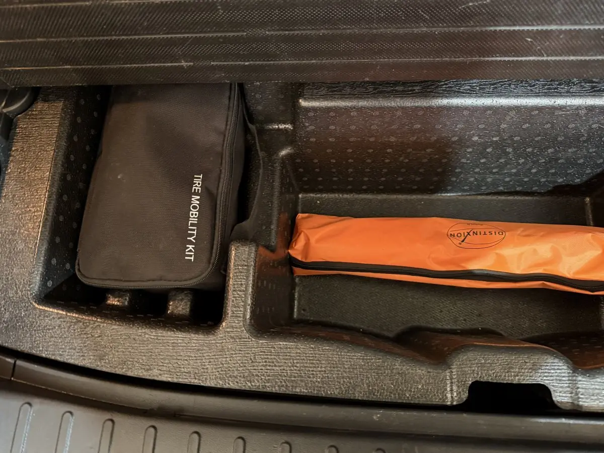 Compartiment de coffre du Hyundai Tucson 2021 noir avec kit mobilité pneus noir et trousse orange de sécurité.