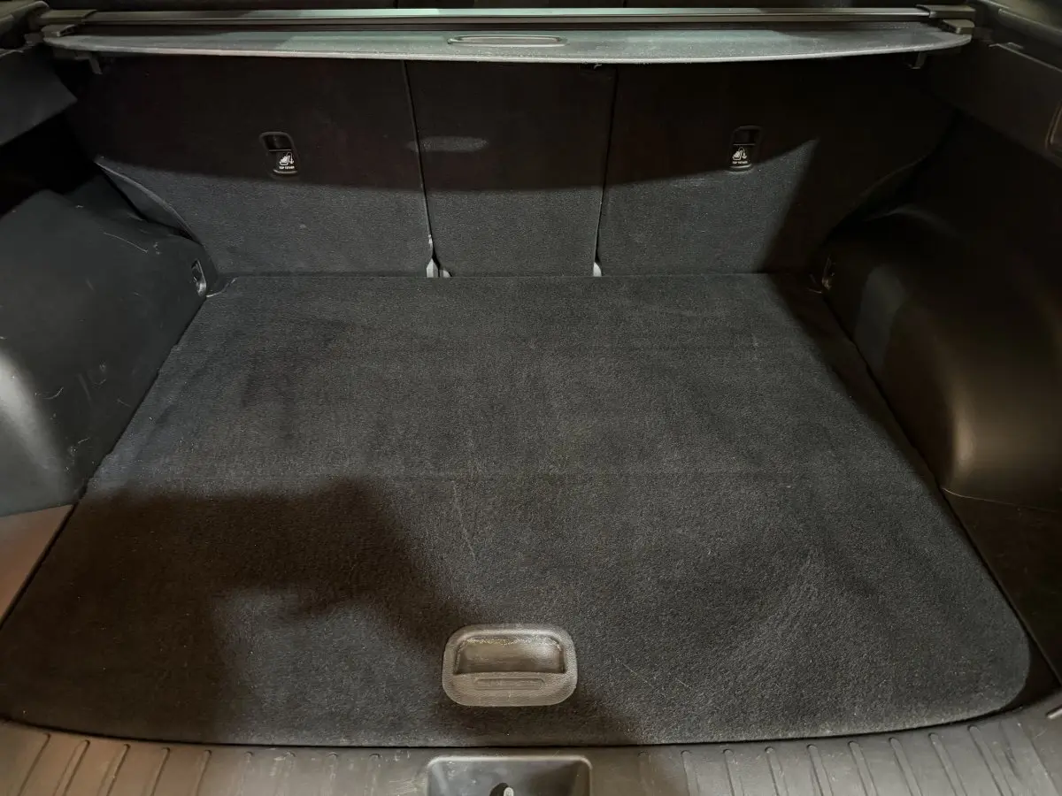 Coffre noir du Hyundai Tucson 2021 vu de face, montrant l'espace de chargement avec tapis et sièges arrière rabattus.