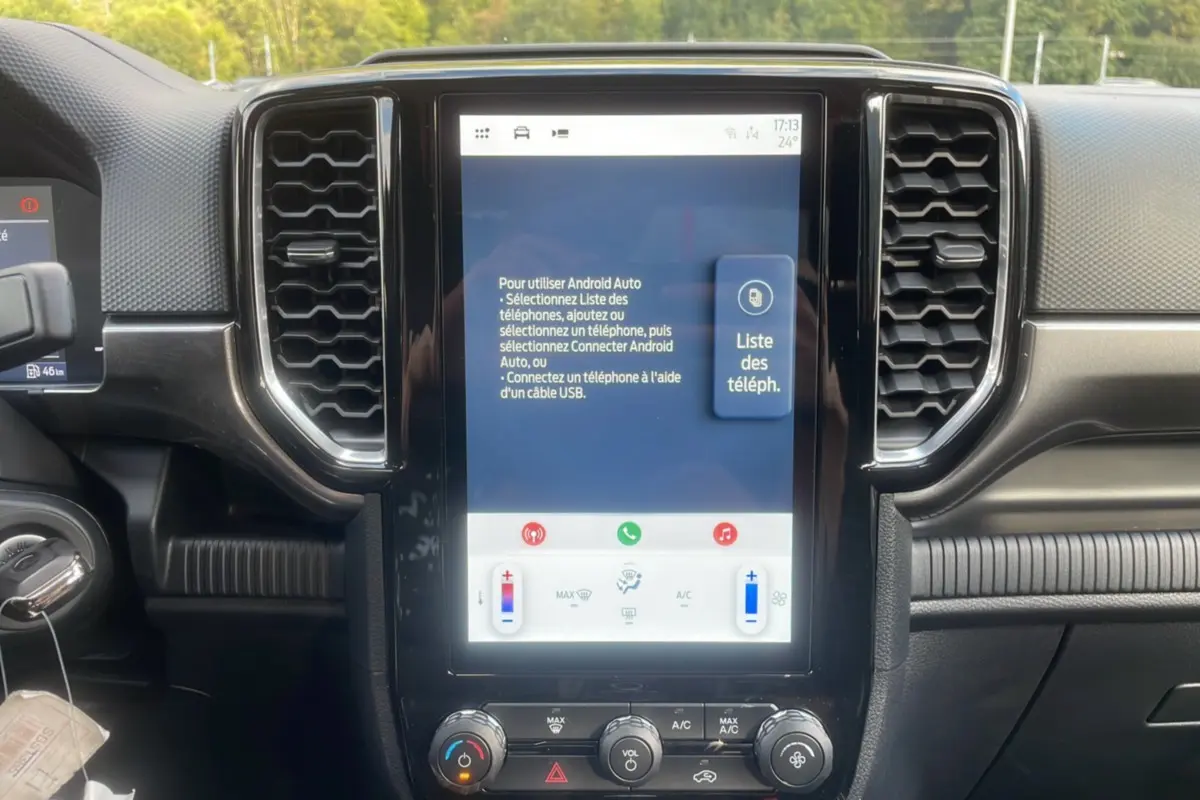 Vue rapprochée du tableau de bord noir du Ford Ranger 2025, mettant en valeur l'écran tactile central et les commandes climatisation.