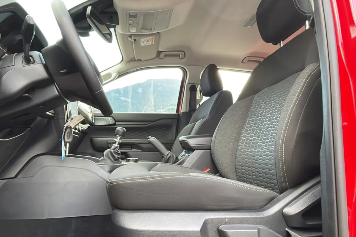 Intérieur du Ford Ranger 2025 rouge racing, vue côté gauche sur sièges avant et levier de vitesses manuel.