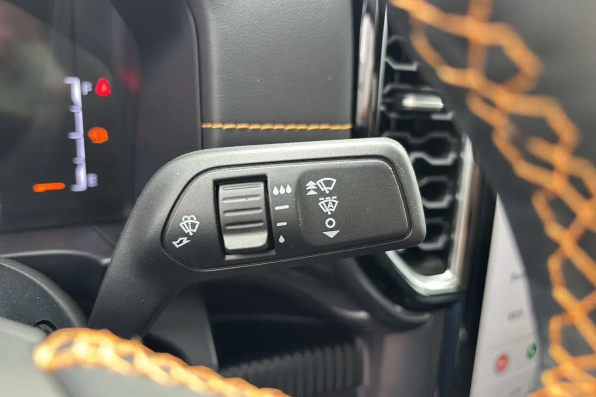 Gros plan sur la commande des essuie-glaces du Ford Ranger 2025, intérieur avec surpiqûres orange visible au volant.