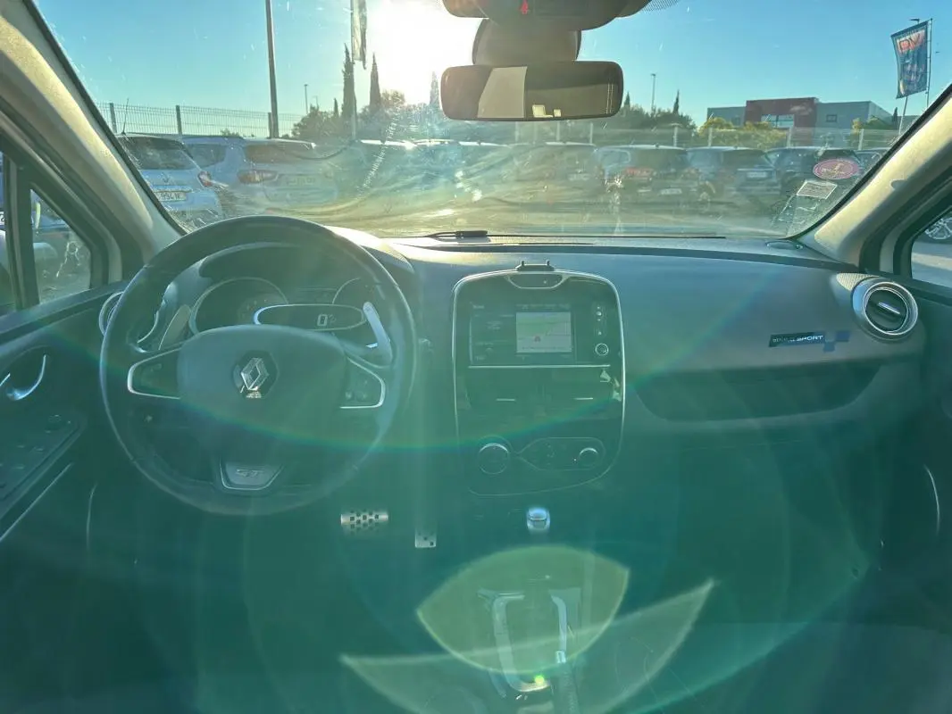 Intérieur avant de la Renault Clio IV TCe 120 GT EDC blanc, tableau de bord avec écran tactile et volant cuir sport.