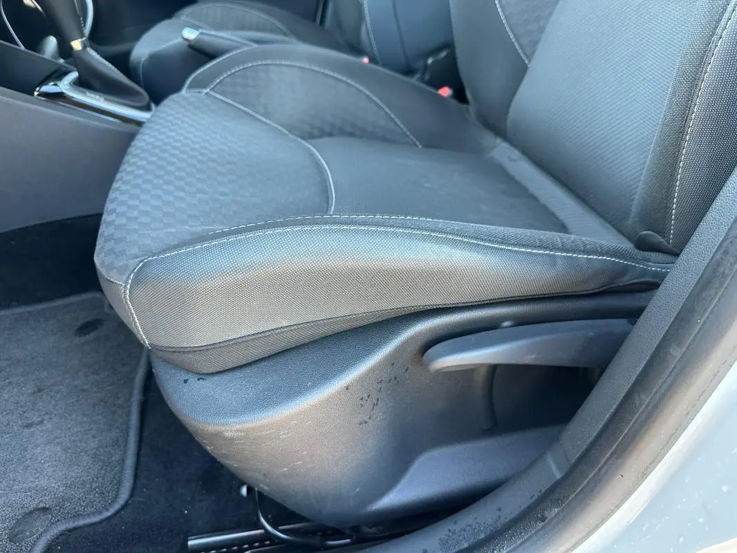 Gros plan sur le siège conducteur en tissu gris foncé de la Renault Clio IV TCe 120 GT EDC blanc, avec réglage manuel.