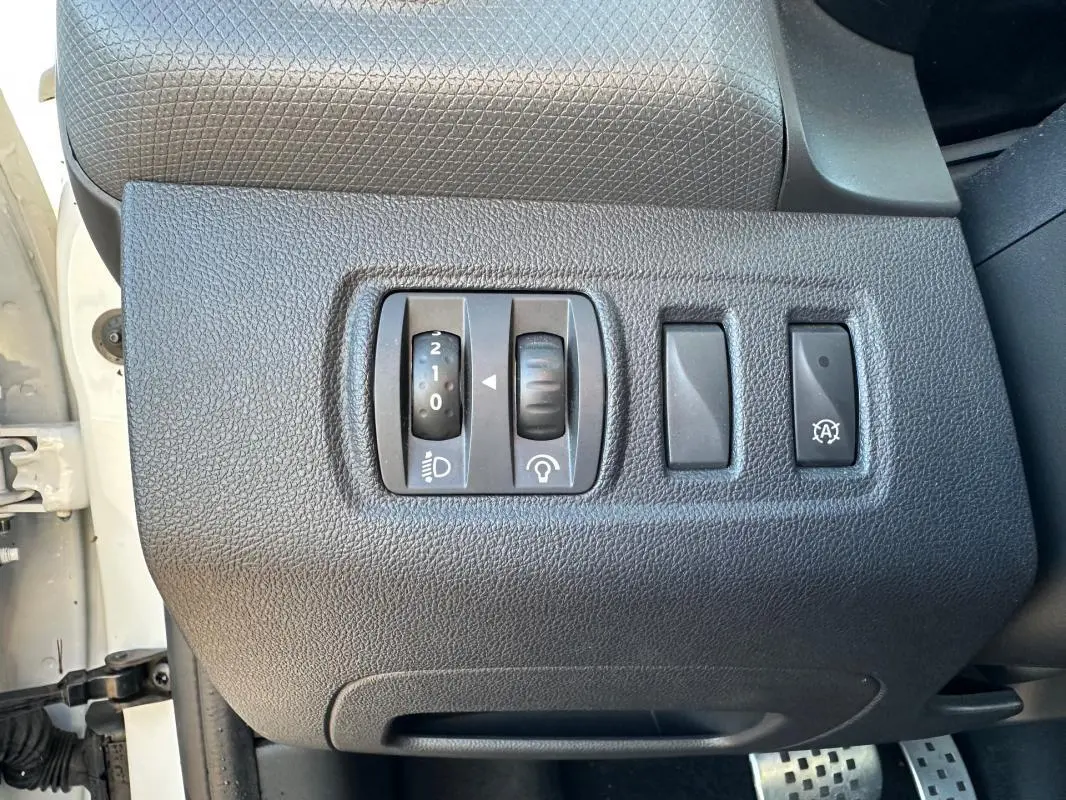Gros plan sur les commandes de réglage d’éclairage et fonction arrêt auto du tableau de bord d’une Renault Clio IV blanche.