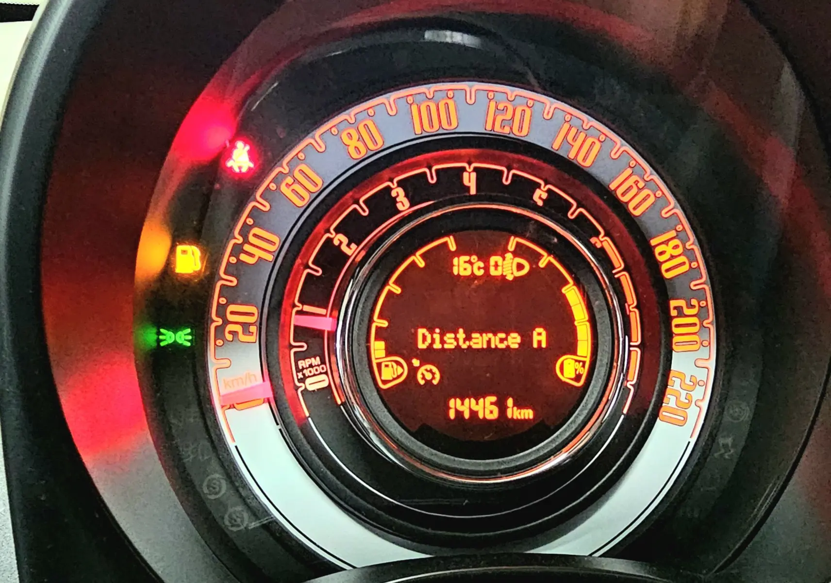 Vue rapprochée du tableau de bord numérique orange de la FIAT 500 2023 affichant 1446 km et température 16°C.