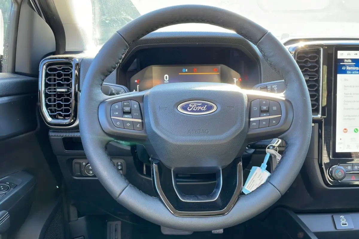 Vue intérieure centrée sur le volant cuir multifonctions du Ford Ranger 2025 avec tableau de bord digital et écran tactile.