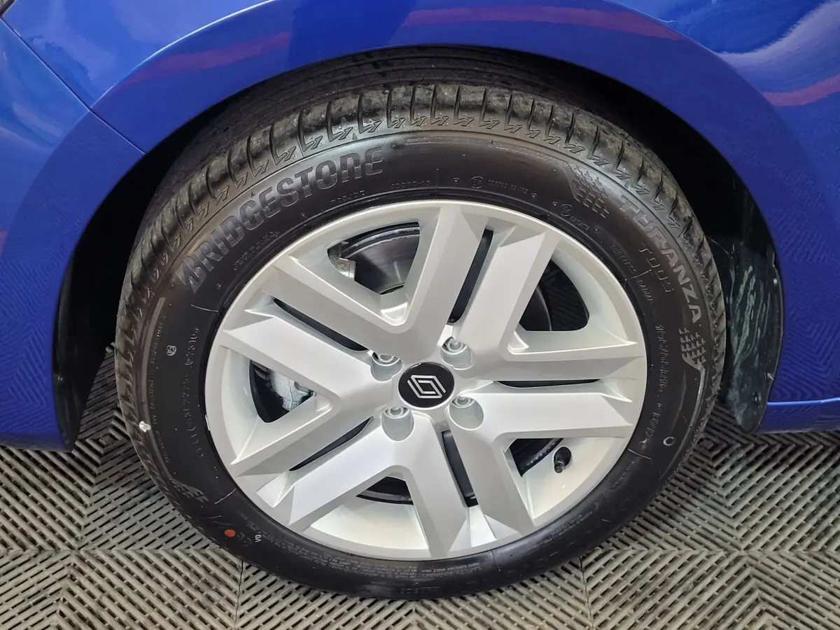 Gros plan sur la roue avant droite d'une Renault Clio bleu 2025 avec jante argentée au design moderne.