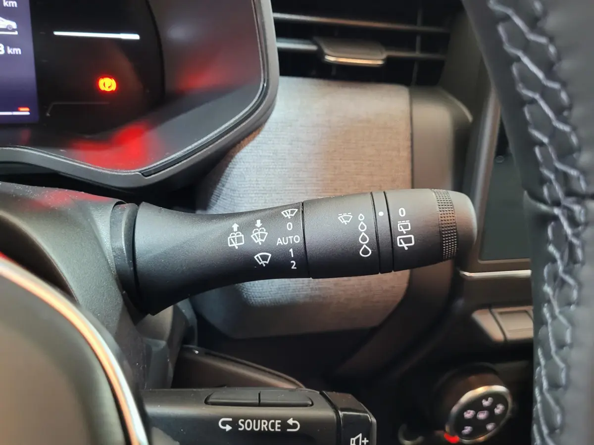 Gros plan sur la manette d'essuie-glace à gauche du volant dans l'habitacle d'une Renault Clio bleu 2025.