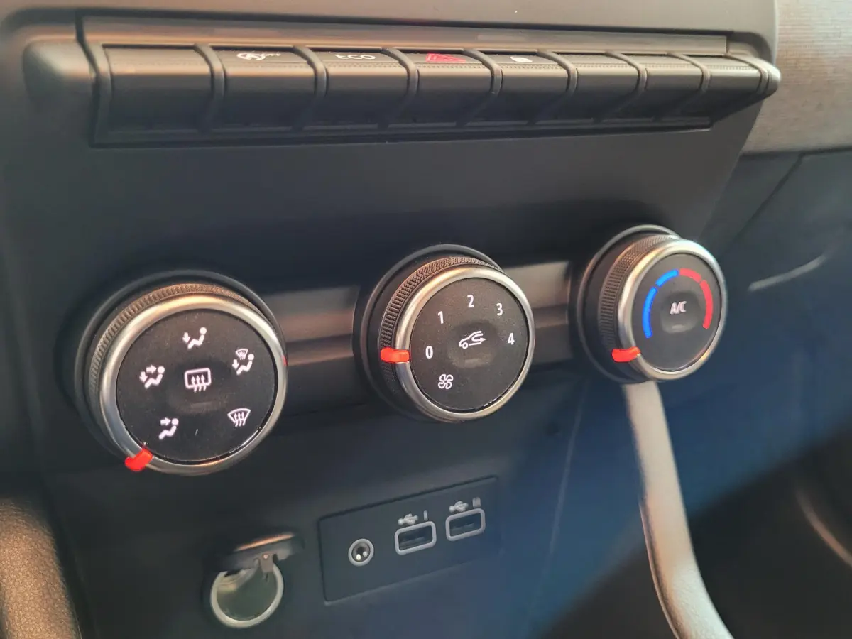 Gros plan sur les commandes de climatisation et ports USB de la Renault Clio Evolution Blue dCi 100, intérieur noir.