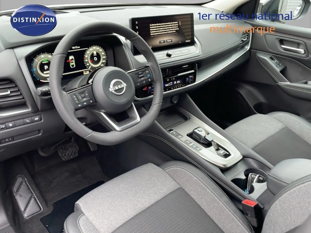 Vue intérieure côté conducteur du Nissan Qashqai 2025, tableau de bord numérique et sellerie tissu gris.