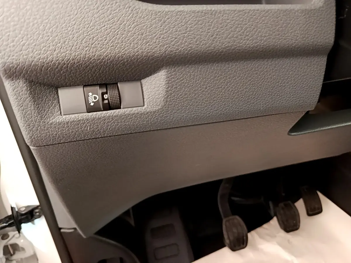 Détail intérieur côté gauche du Peugeot Traveller blanc 2018 montrant le réglage des phares et les trois pédales manuelles.