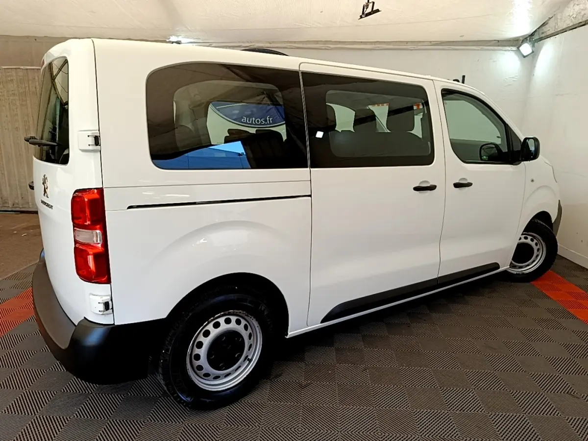 Vue 3/4 arrière droite d’un Peugeot Traveller blanc de 2018 avec vitres teintées et jantes acier noires.