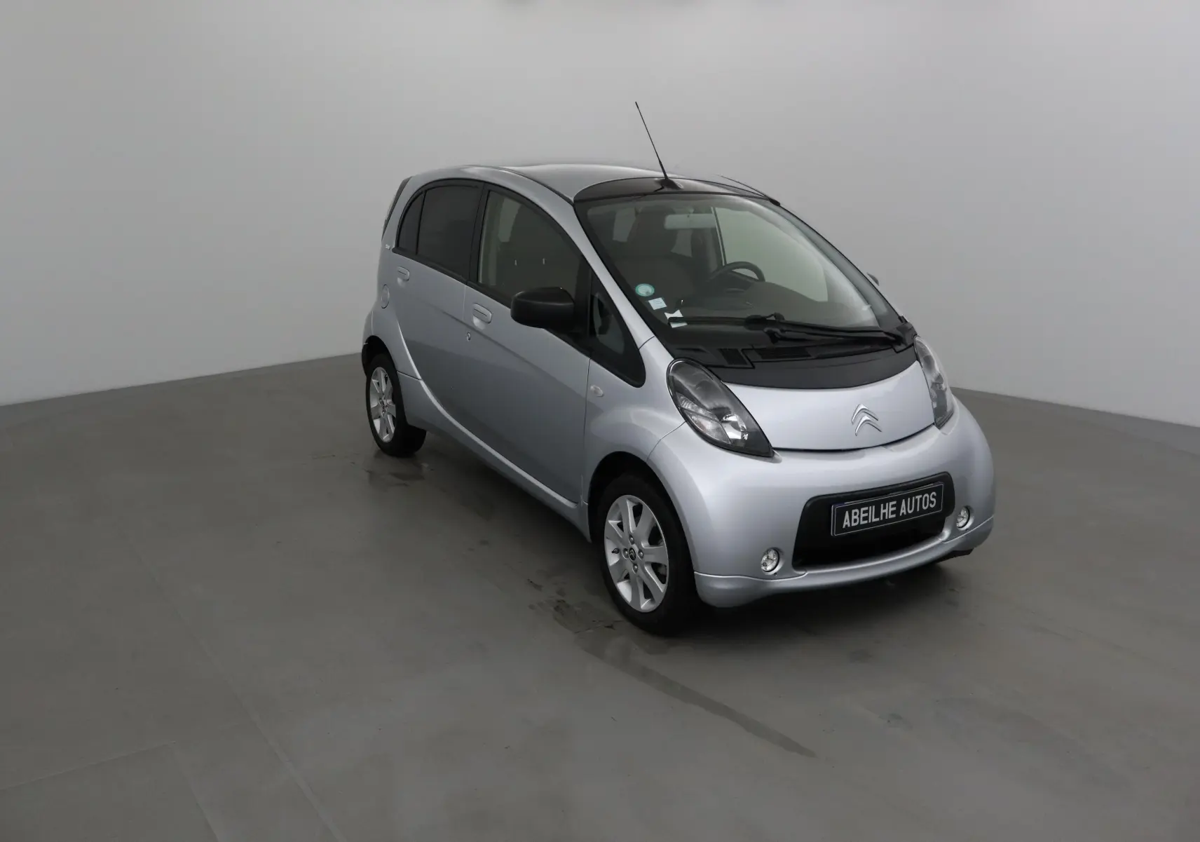Citroën C-Zero gris alu vue 3/4 avant droit dans un studio, compacte et électrique avec jantes alliage.