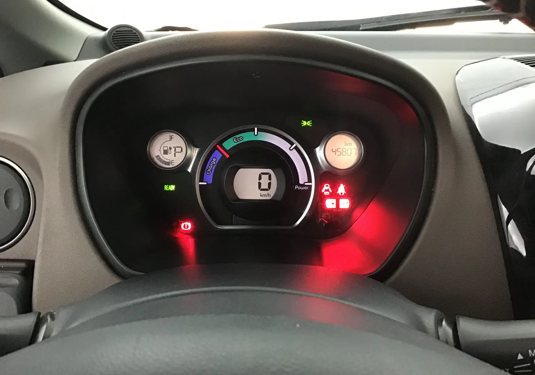 Vue rapprochée du tableau de bord numérique gris alu de la Citroën C-ZERO électrique avec affichage du compteur et témoins allumés.