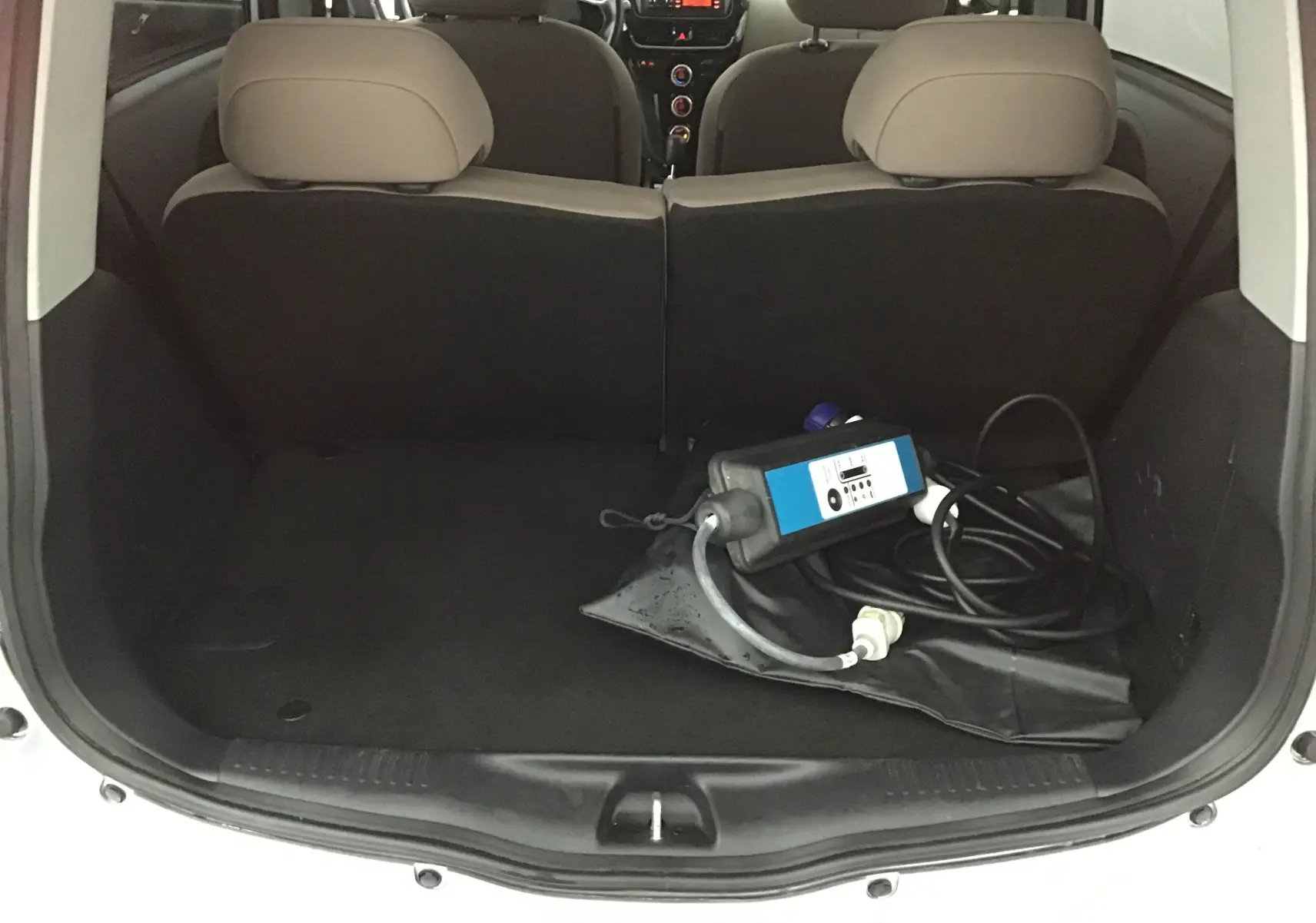 Coffre ouvert d'une Citroën C-ZERO gris alu, vue arrière montrant câble de charge électrique rangé à l'intérieur.