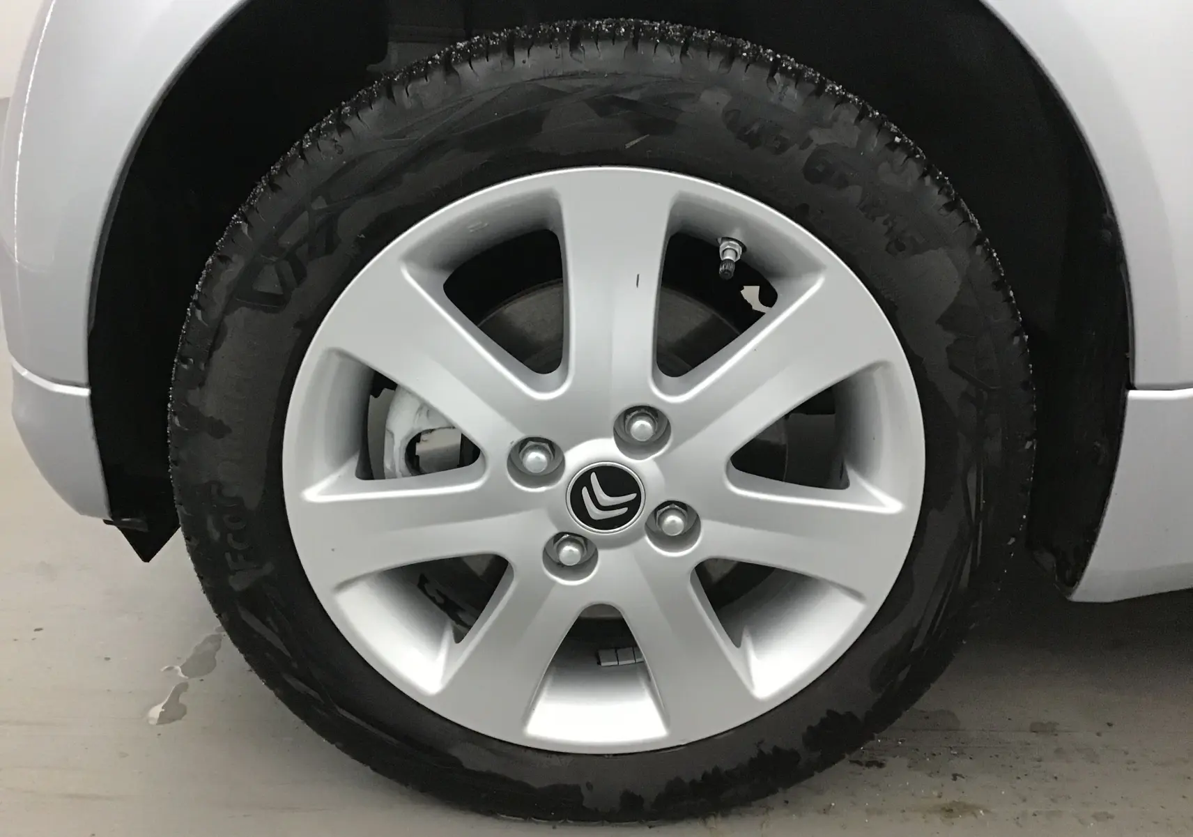 Gros plan sur la roue avant gauche grise alu d'une Citroën C-ZERO électrique 2018 avec jante en alliage et logo Citroën central.