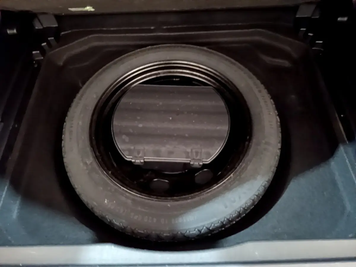 Gros plan sur la roue de secours noire logée dans le coffre d'un Citroën C5 Aircross gris foncé.