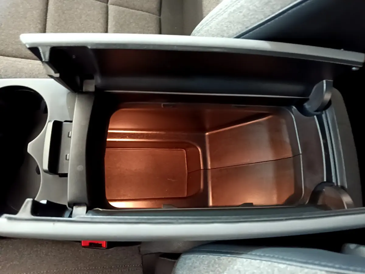 Vue plongeante sur l'accoudoir central ouvert du Citroën C5 Aircross gris foncé, révélant un espace de rangement intérieur.