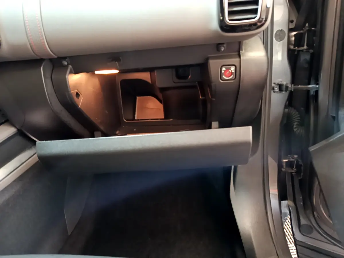 Intérieur côté passager du Citroën C5 Aircross gris foncé, boîte à gants ouverte avec éclairage intérieur visible.