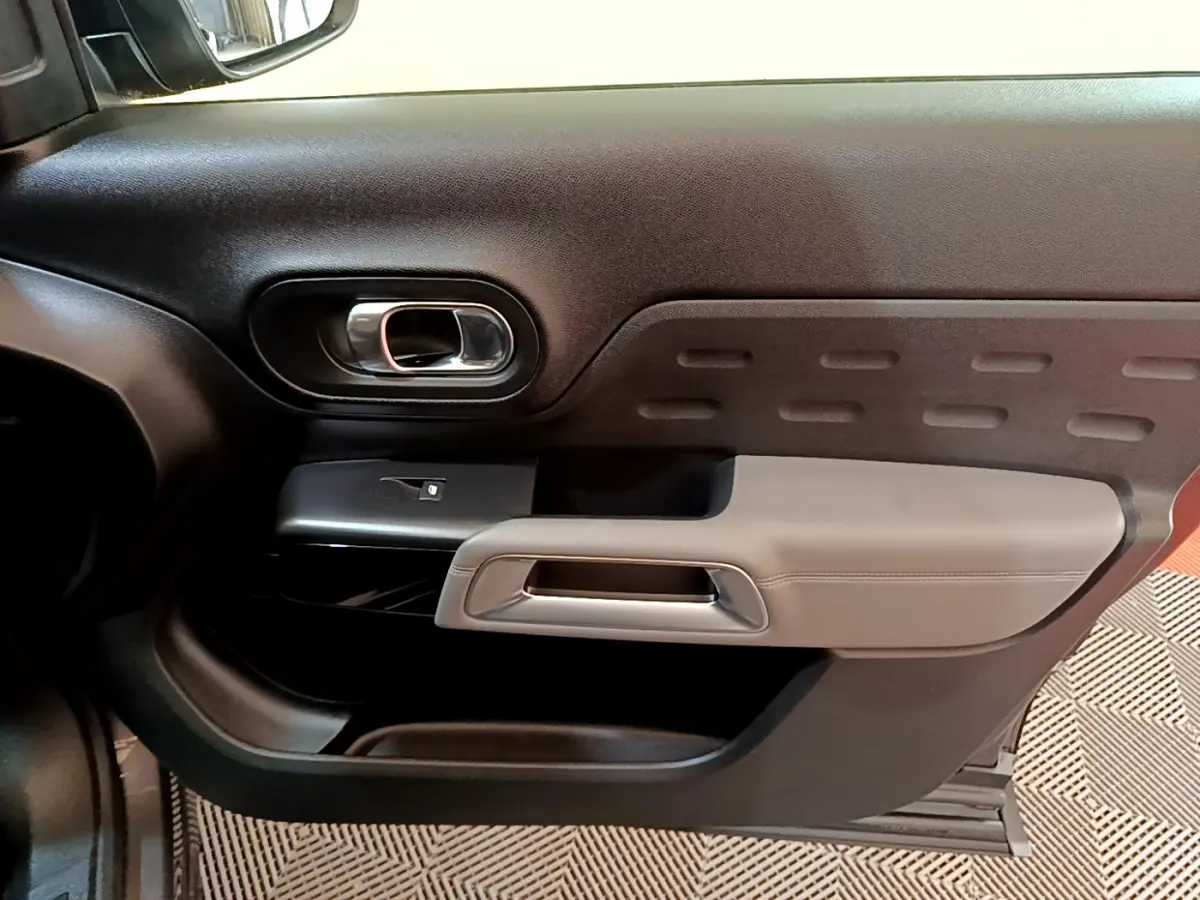 Gros plan sur la porte intérieure côté gauche du Citroën C5 Aircross 2020 gris foncé avec accoudoir beige et poignée chromée.