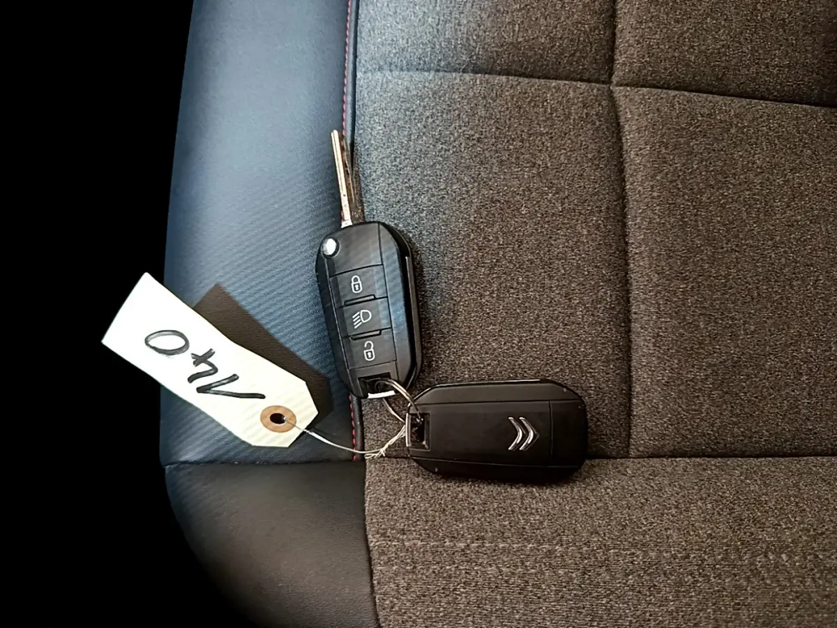 Clé de voiture Citroën posée sur siège tissu gris foncé avec surpiqûres rouges, intérieur du C5 Aircross 2020